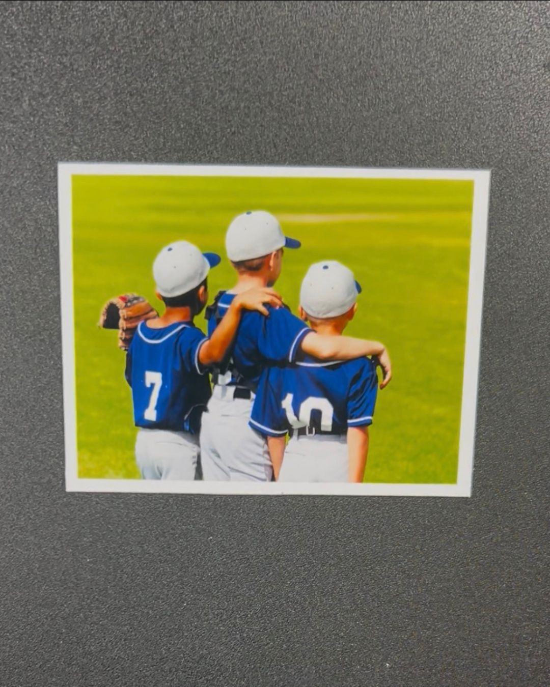Three baseball players in blue uniforms hugging on a field
