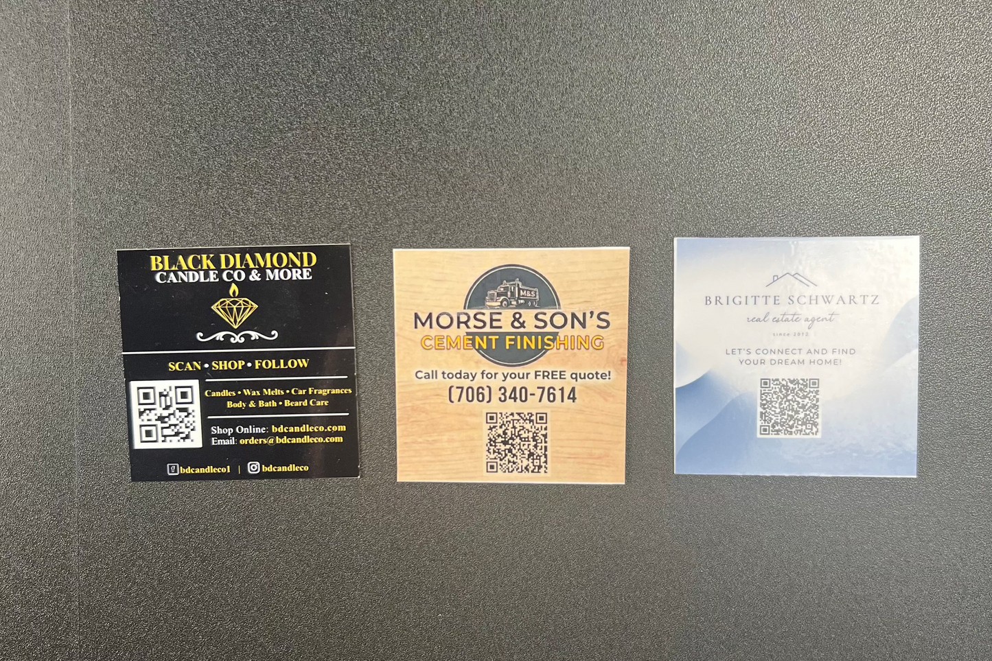 Three business branding cards on a gray surface
